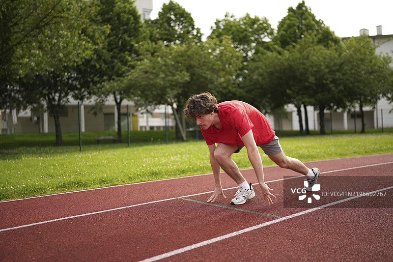 一名年轻的白人男性在跑道起跑线的起始位置上全身像。图片素材
