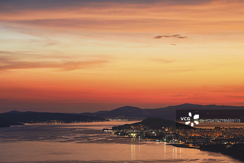 克罗地亚达尔马提亚斯普利特的海滨小镇黄昏全景，背景是山脉，天空中呈现温暖的色彩。图片素材