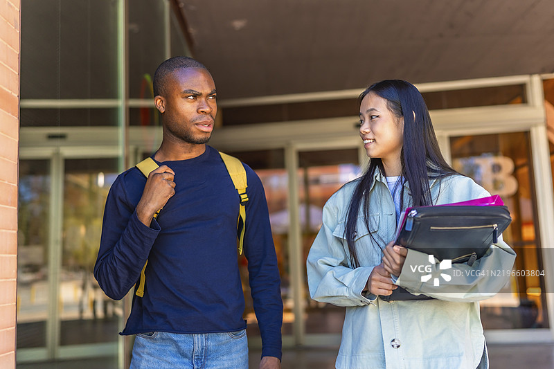 多民族的非洲和中国学生在大学外交谈并走出校园图片素材