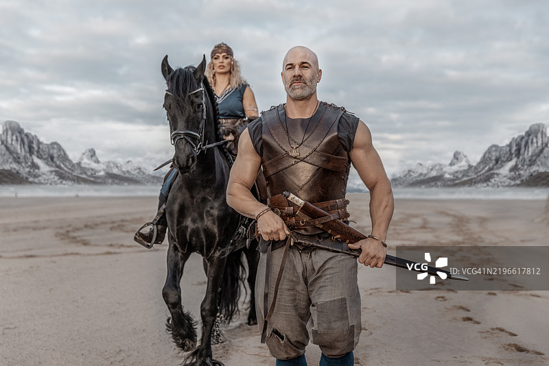 一对美丽的维京战士情侣在海滩上与马匹和山脉相伴图片素材