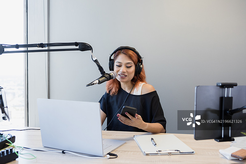 年轻女性播客主持人使用笔记本电脑和麦克风图片素材
