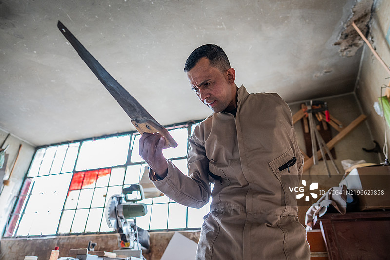 截肢木匠在木工车间握着手锯图片素材