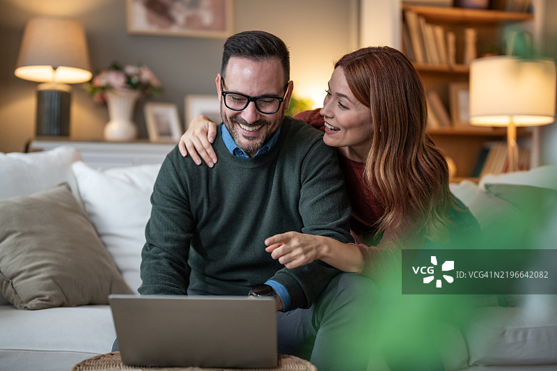 年轻情侣在客厅沙发上浏览互联网图片素材
