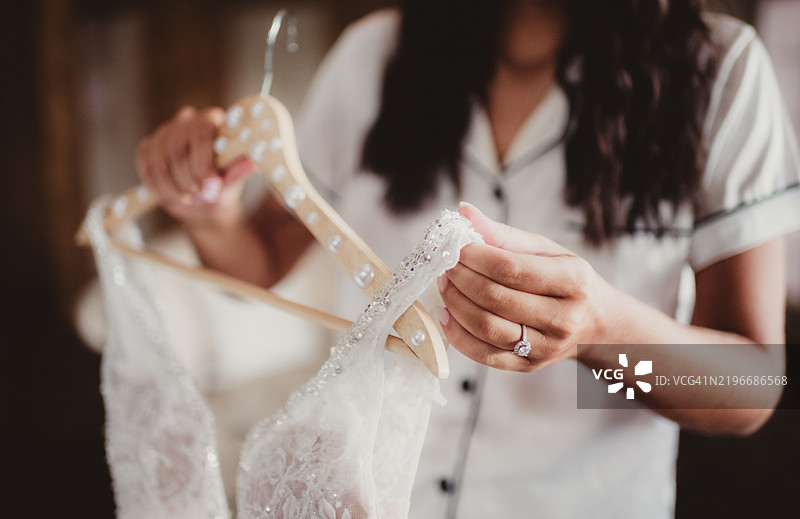 新娘穿着睡衣，手里拿着婚纱。图片素材