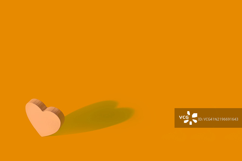 浅橙色心形在鲜艳背景上投下阴影图片素材