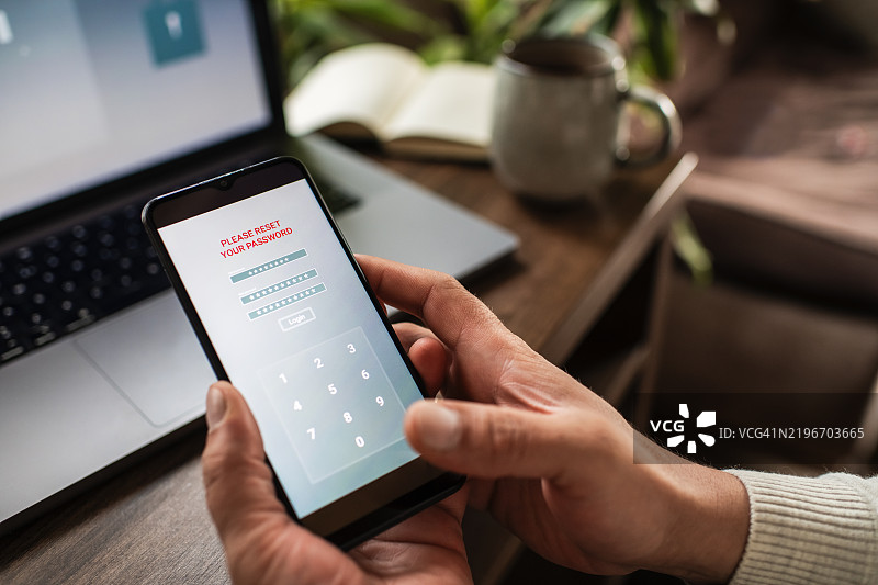 男子使用智能手机和笔记本电脑尝试重置密码。数据安全、数据泄露和未经授权访问的概念。图片素材