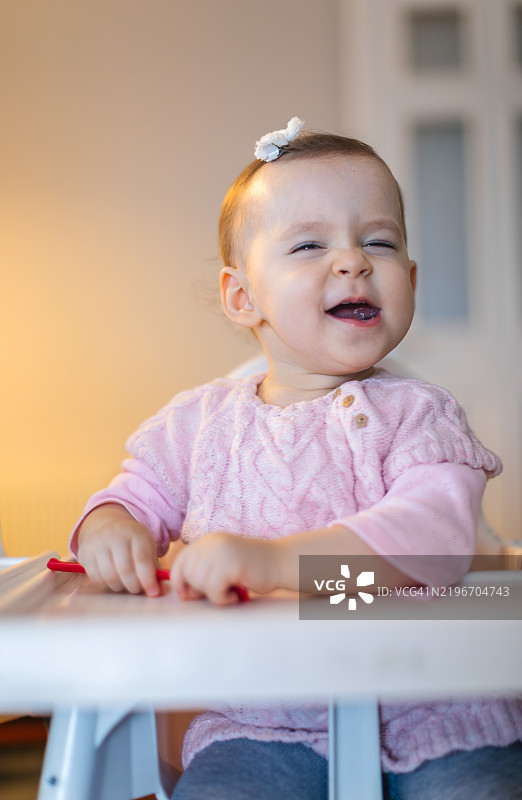 坐在高脚椅上的快乐小女孩的肖像图片素材
