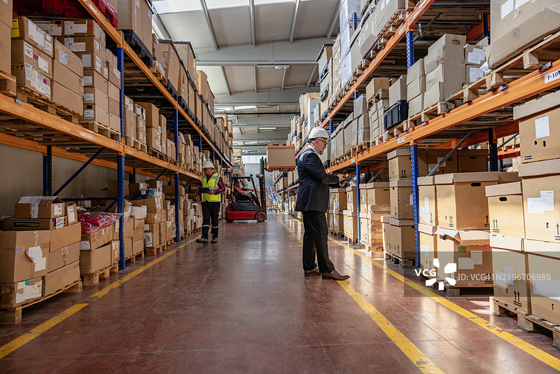 仓库中使用数字平板的工厂经理图片素材