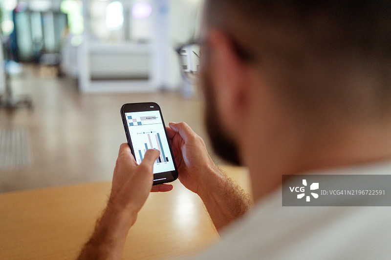 商人近距离拍摄，使用智能手机查看屏幕上的图表图片素材