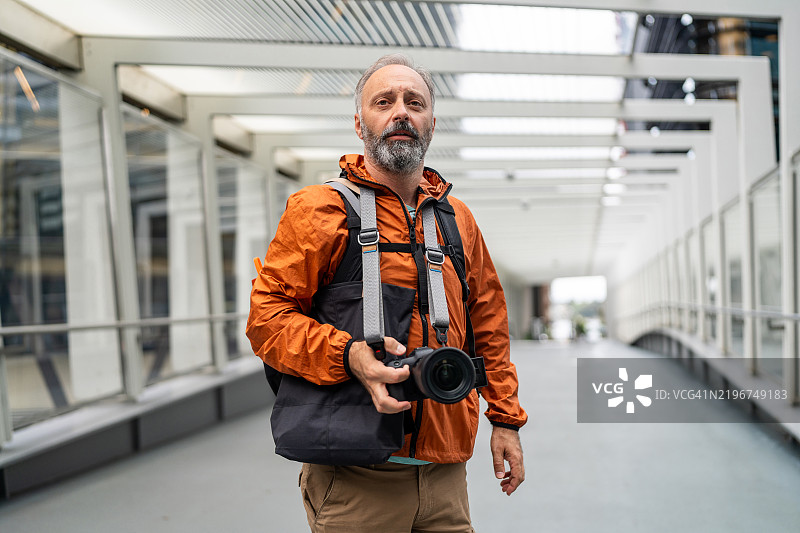 在城市环境中自信地握着单反相机的专业摄影师图片素材