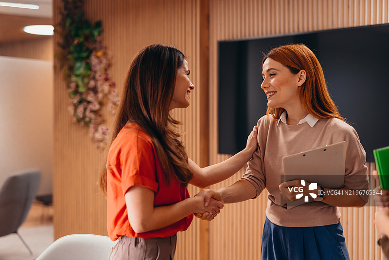 两位女商人在办公室会议期间握手图片素材