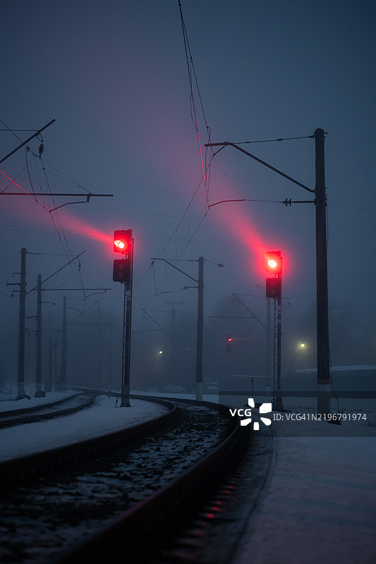 夜间雾中红色信号的铁路交通灯。两盏发出红光的信号灯在铁路上。图片素材