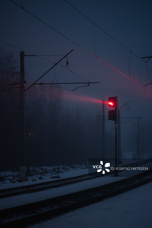 浓雾笼罩着铁路道口，红色信号灯穿透黄昏。空荡荡的站台上是一个雪夜。图片素材