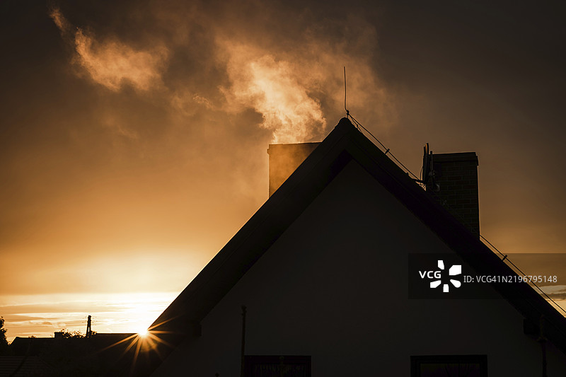 日落时分，房屋烟囱冒出的烟雾图片素材