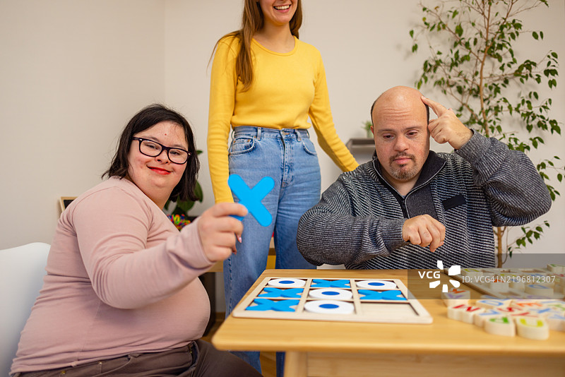 指导成年人参与有趣活动的唐氏综合症助手图片素材