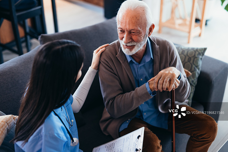 护士在家中安慰手持拐杖的老年男性图片素材