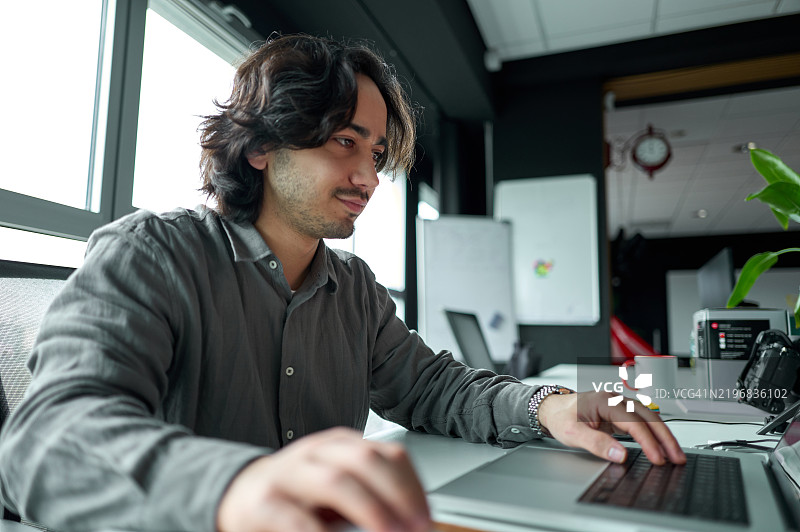 专注的年轻人在现代办公室使用笔记本电脑图片素材