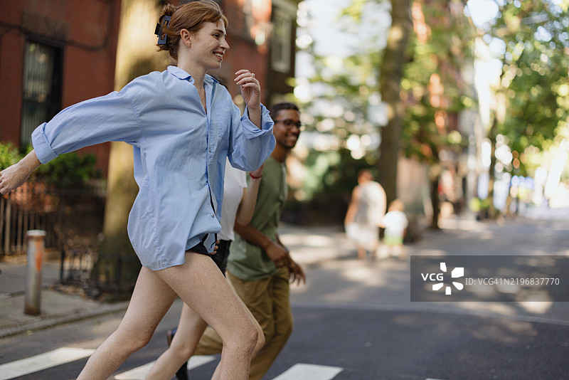 朋友们在阳光明媚的日子里愉快地穿越人行道图片素材