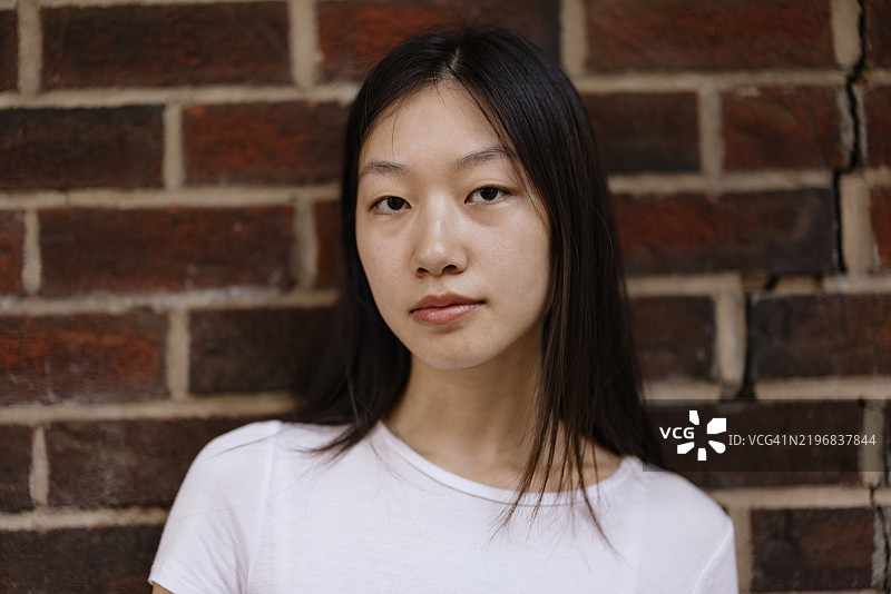 年轻女性在砖墙前的肖像图片素材