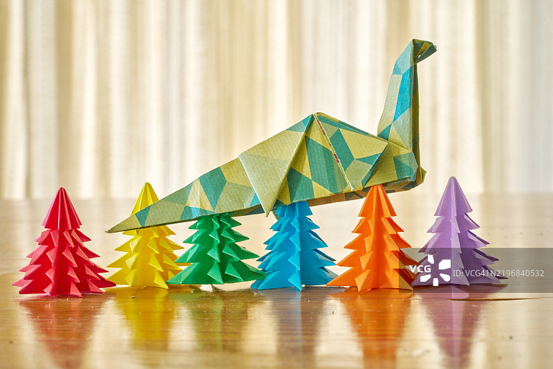 五棵小型折纸圣诞树上 delicately balanced 的多彩折纸恐龙图片素材