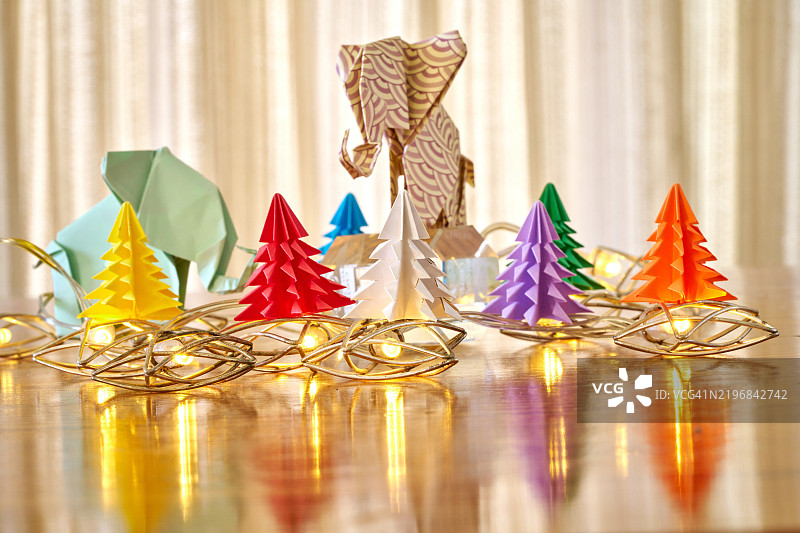 一只折纸大象矗立在一组较小的折纸圣诞树中间图片素材