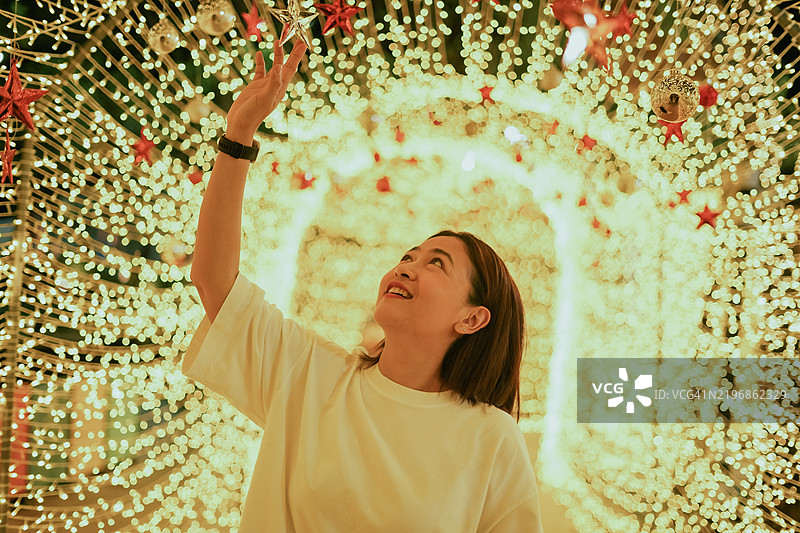 女性沿着小路走，欣赏美丽的装饰灯光。图片素材