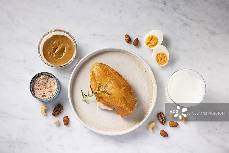 高蛋白食物的选择。俯视图展示鸡胸肉和其他富含蛋白质的食物。图片素材