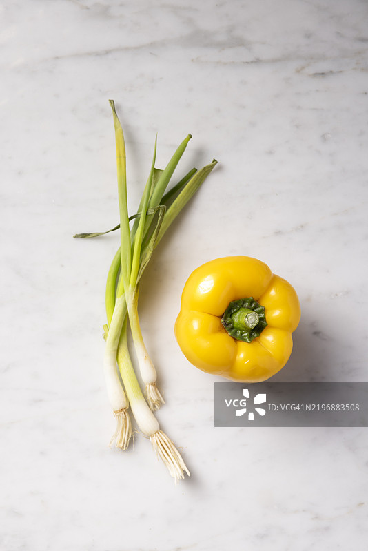 新鲜的春葱和辣椒放在大理石背景上。图片素材