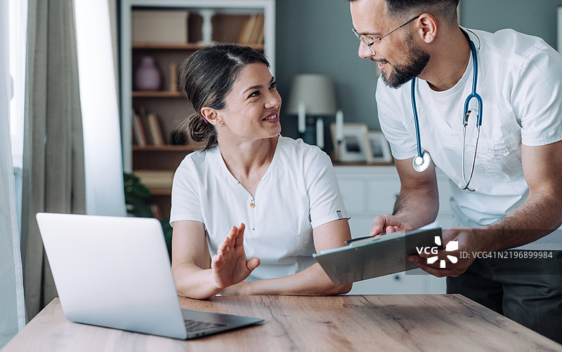 快乐的医疗专家在办公室使用笔记本电脑工作。图片素材