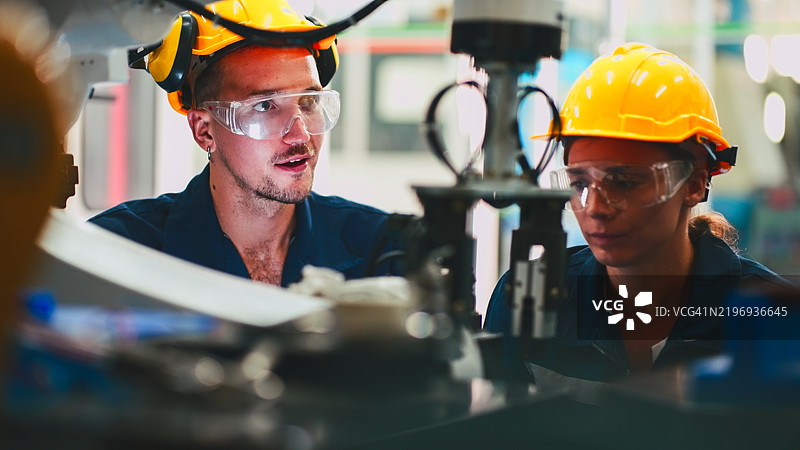 工程师团队在实验室中使用数字平板电脑与机器人手臂进行维护，并分析静态数据图表信息。图片素材