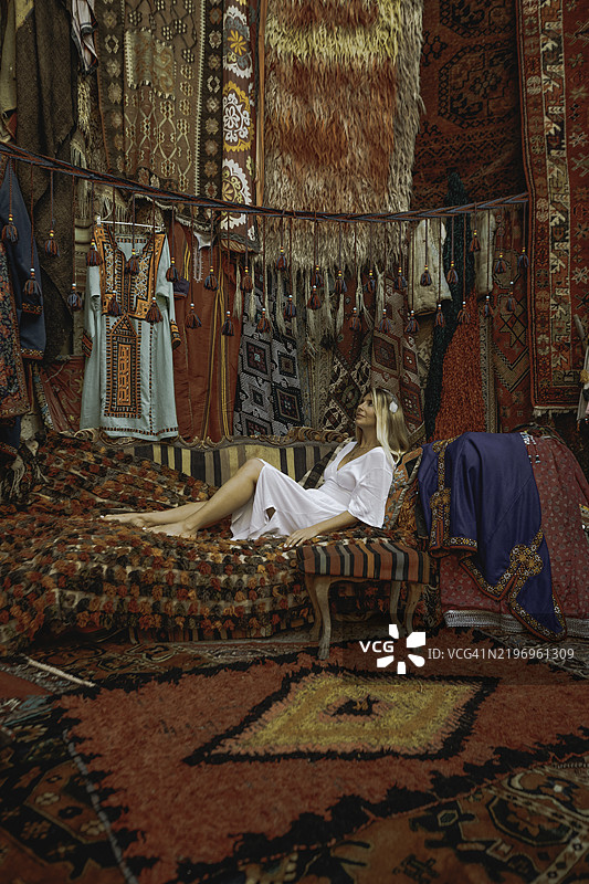 在土耳其传统集市中，游客女性在手工土耳其地毯中放松。图片素材