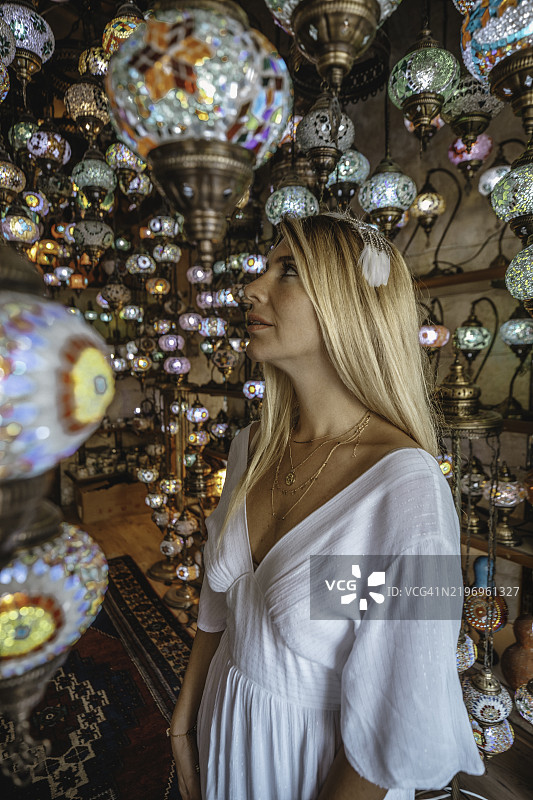 年轻的独自旅行者在土耳其卡帕多奇亚的集市上欣赏手工马赛克灯饰的肖像图片素材