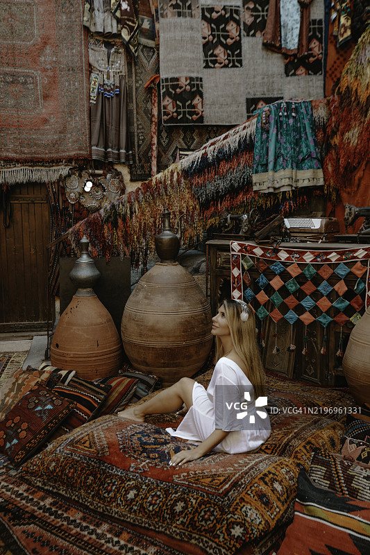 在土耳其传统集市中，游客女性在手工土耳其地毯中放松。图片素材