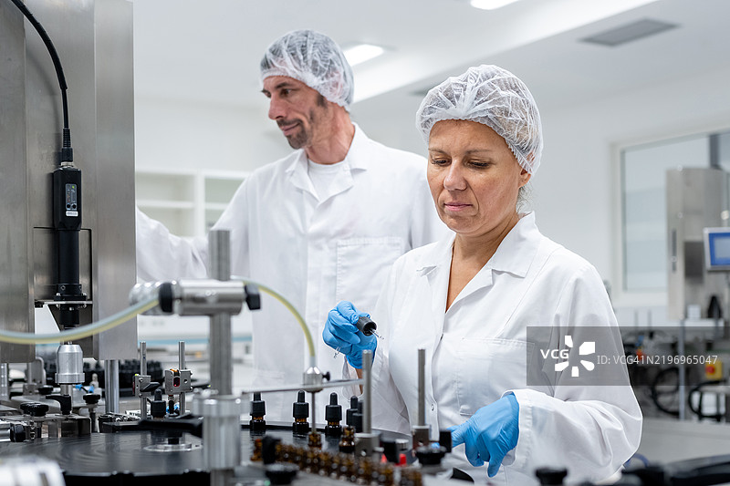 制药工人在生产线上进行瓶子的灌装和包装。图片素材