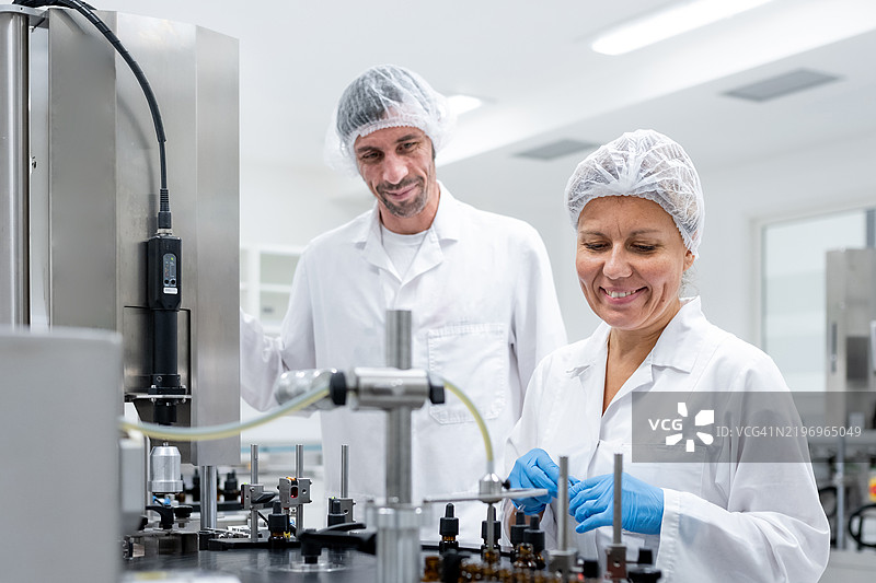 制药工人在生产线上进行瓶子的灌装和包装。图片素材