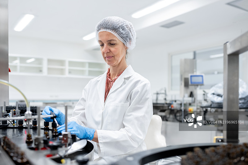 制药工人在生产线上进行瓶子的灌装和包装。图片素材