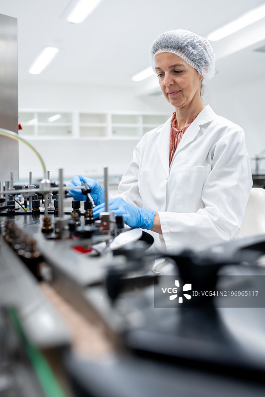 制药工人在生产线上进行瓶子的灌装和包装。图片素材