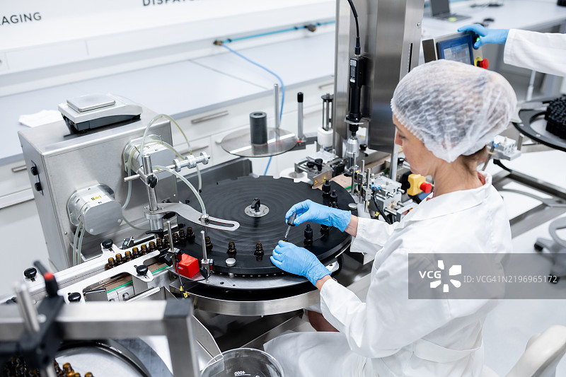 制药工人在生产线上进行瓶子的灌装和包装。图片素材