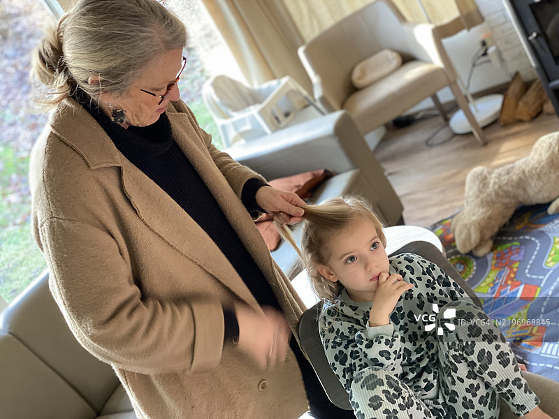 祖母为孙女护理头发。图片素材