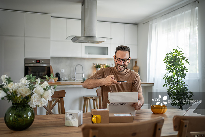 一个快乐的男人查看刚刚送到他家地址的在线订单图片素材