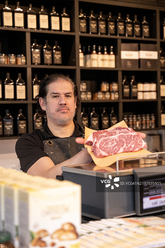 肉店里持有牛排的屠夫肖像图片素材