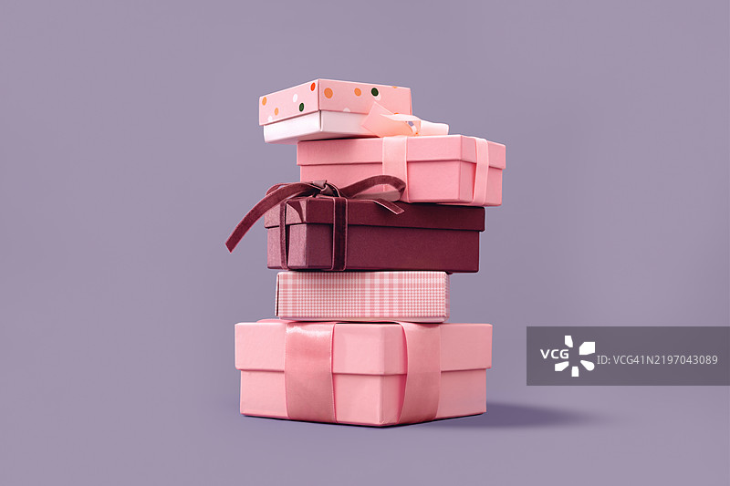 几只粉色礼品盒叠放在柔和的紫丁香色背景上图片素材