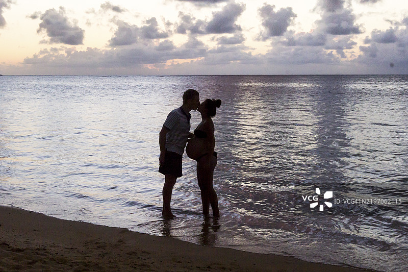 海滩上男人和孕妇的剪影照片图片素材