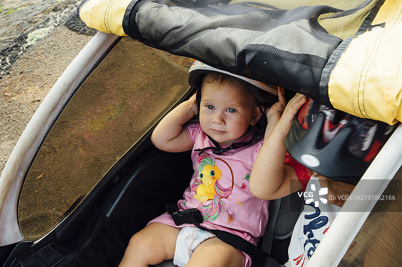 男孩和女孩坐在自行车拖车上，位于人行道上。图片素材