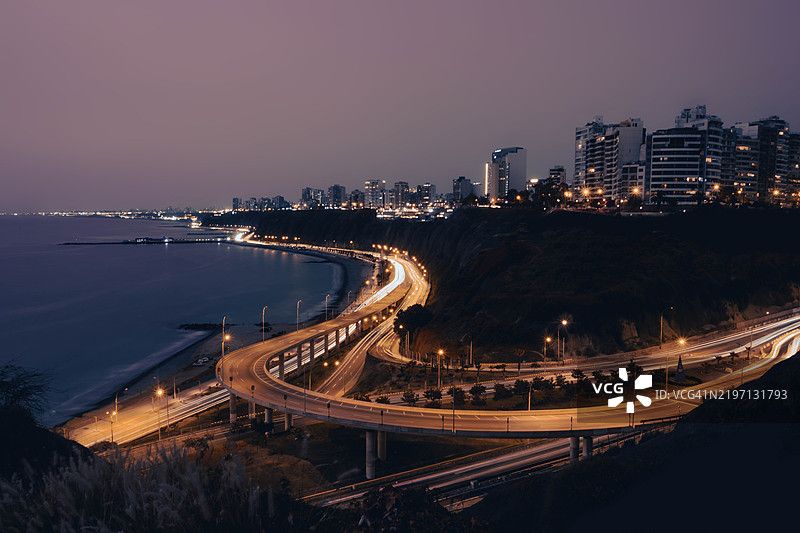 黎明时分的利马天际线，伴随着高架道路和交通灯的光轨图片素材