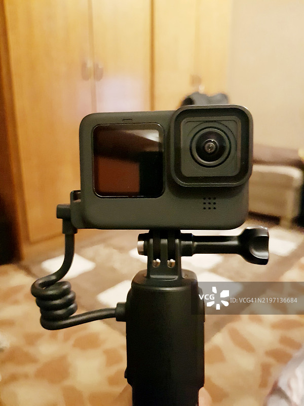 口袋大小的超高清防水运动相机锁定在客厅的GoPro Volta手柄上。图片素材