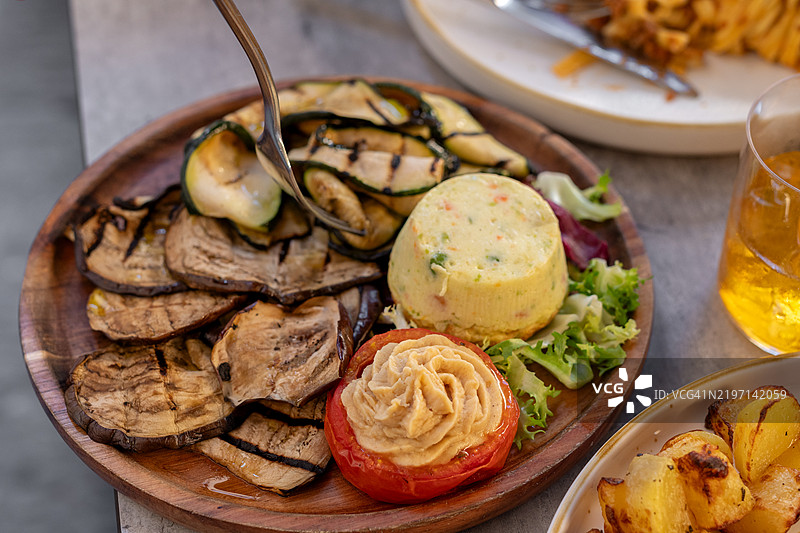 餐厅里的烤蔬菜开胃菜盘，包含烤西葫芦和茄子，配有鹰嘴豆泥和番茄，意大利餐厅的素食开胃菜。图片素材