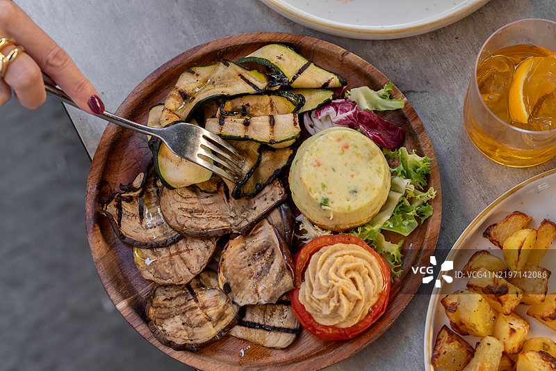 餐厅里的烤蔬菜开胃菜盘，包含烤西葫芦和茄子，配有鹰嘴豆泥和番茄，意大利餐厅的素食开胃菜。图片素材