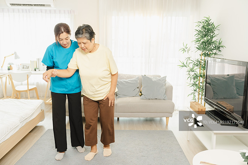 在家中提供老年护理援助，支持性护理人员帮助老年女性安全行走，以改善健康和福祉。图片素材