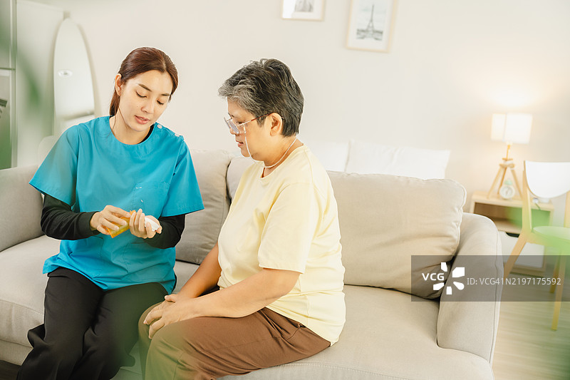 老年护理援助：富有同情心的护理人员在舒适的家庭环境中为一位老年女性提供用药指导。专业支持。图片素材